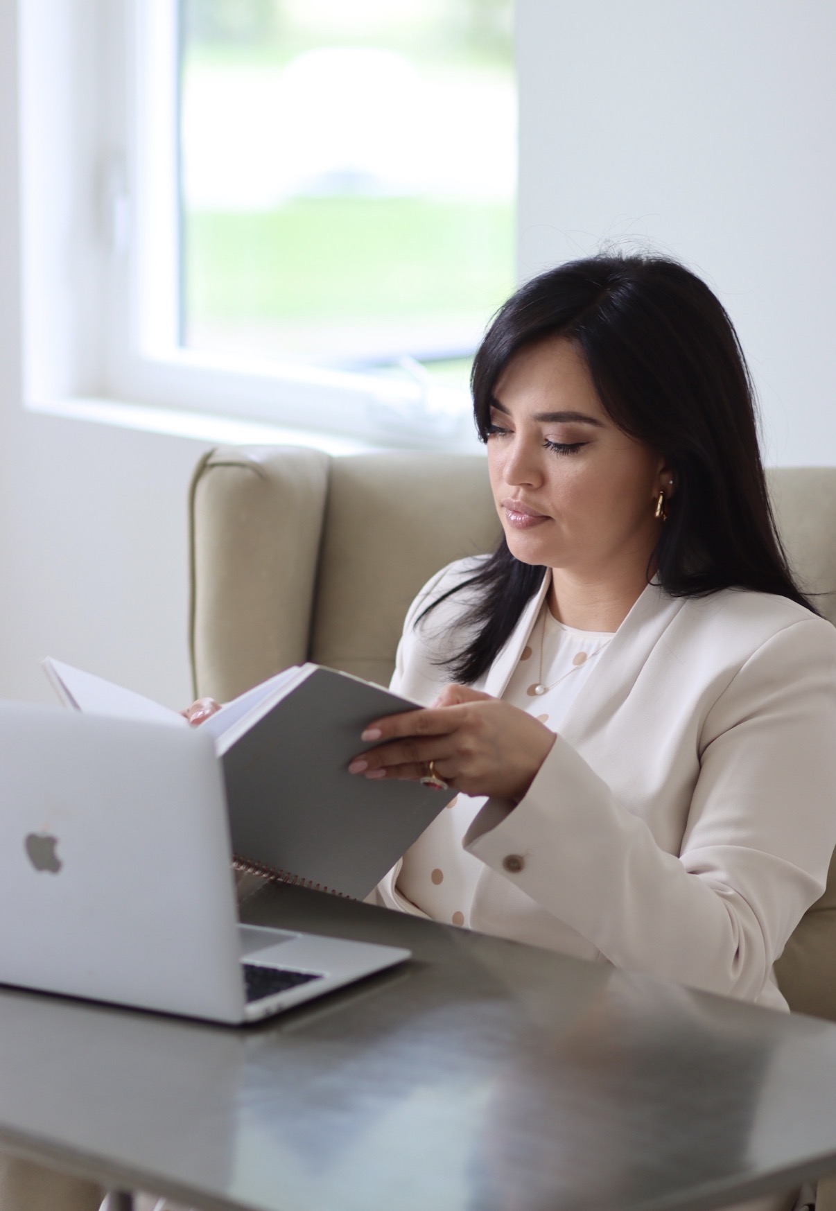 Shakhlo reading her notebook beside a laptop